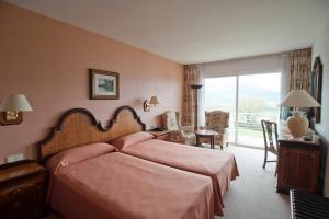 a bedroom with a bed and a desk and a window at Hotel Riu Fluviá in Olot