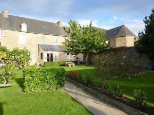 ein großes Haus mit einem Hof mit Gras und Bäumen in der Unterkunft Maison d'Hôtes Les Belles de Mai in Pontorson