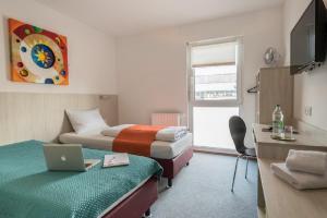 a hotel room with two beds and a laptop on a desk at FairSleep Motel Einstein Erding in Erding