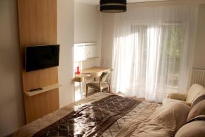 Velence Resort Apartman في فيلينس: غرفة نوم بسرير ومكتب ونافذة