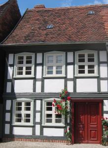 uma casa branca e preta com uma porta vermelha em Ferienhaus St. Johannis em Werben