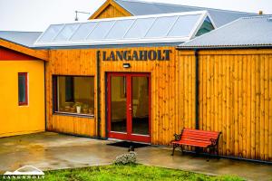 Langaholt的住宿－Hotel Langaholt，前面有长凳的木制建筑