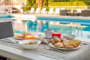 een dienblad met ontbijtproducten op een tafel naast een zwembad bij Hotel Palace Magnolia SPA in Tortoreto Lido