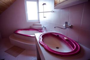 y baño con bañera rosa y aseo. en Adonisz Vendégház, en Mórahalom