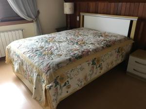 1 dormitorio con 1 cama con colcha de flores en Apartamento Castelinho - Centro, en Gramado