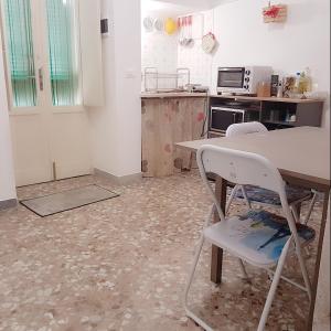 cocina con mesa y 2 sillas blancas en Casa Eleonora, en Monopoli 2 fotos más