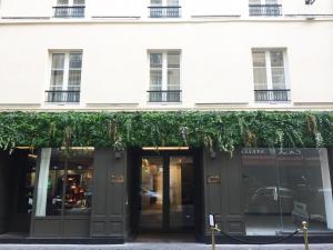 Perpetual Elysée Montaigne في باريس: متجر أمام مبنى أبيض مع اللبي الأخضر