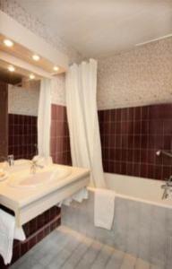 a bathroom with a tub and a sink and a shower at Hotel Adret in Les Deux Alpes