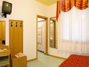 um quarto com uma cama, uma televisão e uma janela em Locanda da Scarpa em Cavallino-Treporti