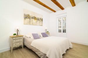 a white bedroom with a large bed with purple pillows at Vivaldi Center City in Valencia