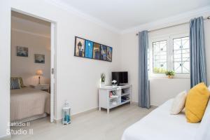 a white bedroom with a bed and a window at Akisol Vilamoura Gold in Vilamoura