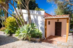 - un petit bâtiment blanc avec une porte marron dans l'établissement Casa da Montanha, à Luz