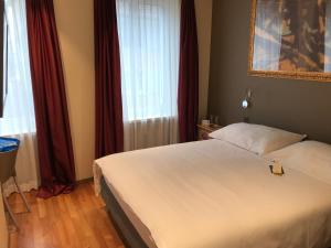 Schlafzimmer mit einem weißen Bett und roten Vorhängen in der Unterkunft Hotel Limmatblick in Zürich