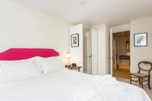 ロンドンにあるALTIDO Stylish 2 Bed, 2 bath flat with patio, near Victoria stationのベッドルーム1室(白いベッド1台、赤いヘッドボード付)