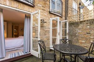 ロンドンにあるALTIDO Stylish 2 Bed, 2 bath flat with patio, near Victoria stationのパティオ(テーブル、椅子付)、ベッドルーム1室が備わります。