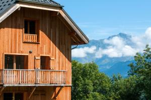 a building with a balcony and mountains in the background at Goélia Les Chalets de Belledonne in Saint-Colomban-des-Villards