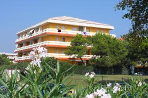 un bâtiment jaune avec des arbres devant lui dans l'établissement Condominio Carina, à Bibione