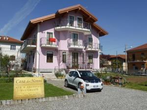 皮亞內札的住宿－Casa dei Nonni，停在粉红色房子前面的汽车