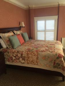 a bedroom with a bed with a floral bedspread and a window at Hotel Mac in Richmond