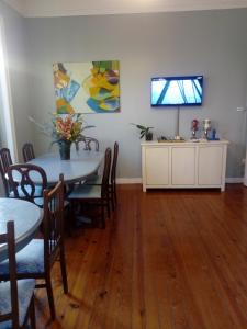 a dining room with a table and a television on a wall at Casa Azul Hostel in Sintra