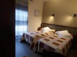 a hotel room with two beds and a window at Hôtel restaurant HENRY in Puy-lʼÉvêque