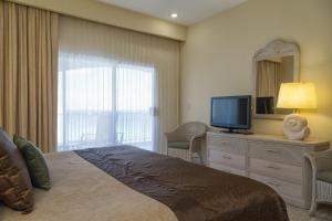 a hotel room with a large bed and a television at The Royal Islander – An All Suites Resort in Cancún