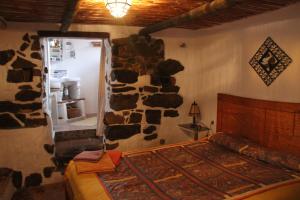 Un dormitorio con una pared de piedra y una cama. en Cinco Lunas Holiday Accommodation, en Zahara de la Sierra