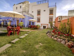 um pátio com uma mesa, cadeiras e um guarda-sol em Las Torres de Ugarte em Arequipa