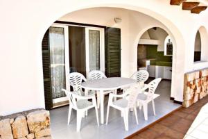a dining room with a table and chairs on a patio at Villa Na y Veni in Cala en Bosc