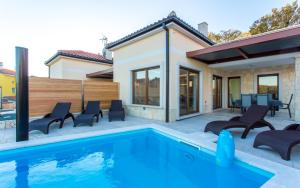 a swimming pool with chairs and a house at Villa Ema in Čižići