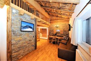 a living room with a tv on a stone wall at Appartement Berghof in Saalbach Hinterglemm