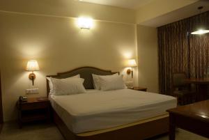 a bedroom with a bed with white sheets and pillows at Comfort Hotels in Coimbatore
