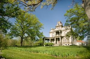 ein altes Haus auf einem Rasen mit Bäumen in der Unterkunft Garth Woodside Mansion Bed and Breakfast in Hannibal