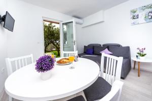 a white dining room with a white table and chairs at Apartments Nika in Cavtat