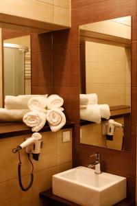 W łazience znajduje się umywalka, lustro i ręczniki. w obiekcie Boutique Hotel's Sosnowiec w mieście Sosnowiec