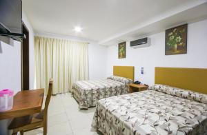 a hotel room with two beds and a desk at Hotel Real del Mar in Veracruz