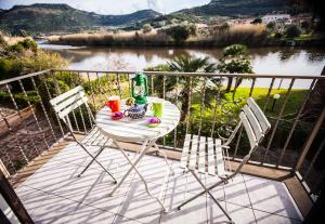 uma mesa e cadeiras numa varanda com vista para um rio em Bosa Apartments "House on the River" em Bosa