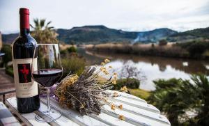 een fles wijn zittend op een tafel met een glas bij Bosa Apartments "House on the River" in Bosa