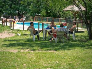 un grupo de personas sentadas alrededor de una mesa junto a una piscina en Casa Grande Hostel en Merlo