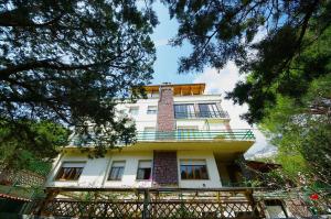 a tall white building with a balcony and trees at La bouganville Apartments in Cala Gonone