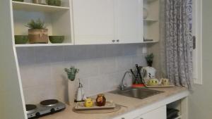 a kitchen counter with a sink and white cabinets at Ammos Apartments in Ierápetra