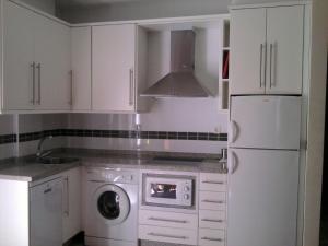 eine Küche mit weißen Schränken und einer Waschmaschine in der Unterkunft Cozy Loft Torremolinos in Torremolinos