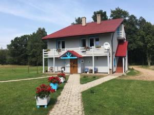ein Haus mit rotem Dach und Blumen davor in der Unterkunft Dom na Starym Gościńcu Tiszyna in Dubicze Cerkiewne