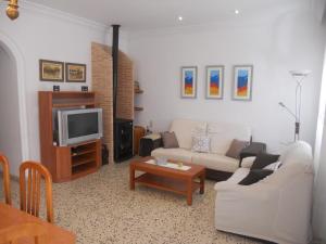 sala de estar con sofá blanco y TV en Chalet cerca del mar, en Playa de Miramar