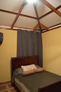 1 dormitorio con 1 cama con cortina azul en Casita Amarilla, en Cahuita