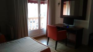 Cette chambre comprend un lit, un bureau et une fenêtre. dans l'établissement Hotel Alfageme, à Trobajo del Camino