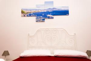 ナポリにあるO' sole e' Napuleの白いベッド1台、壁に絵画2点が備わるベッドルーム1室