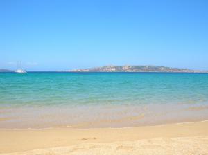 a beach with the ocean and a boat in the water at Le case di Stella Maris in Palau