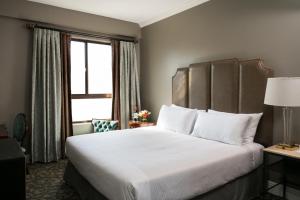 a hotel room with a bed, chair, and nightstand at Hotel Bijou, WorldHotels Crafted in San Francisco