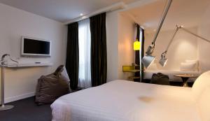 パリにあるカラー デザイン ホテルのベッドとテレビ付きのホテルルーム
